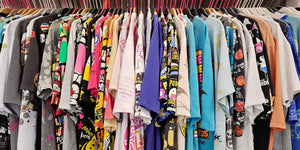 Colourful t-shirt collection on hangers with diverse designs.